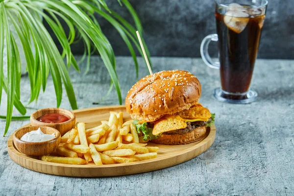 Big burger with fry potato in the wooden plate on the marble background