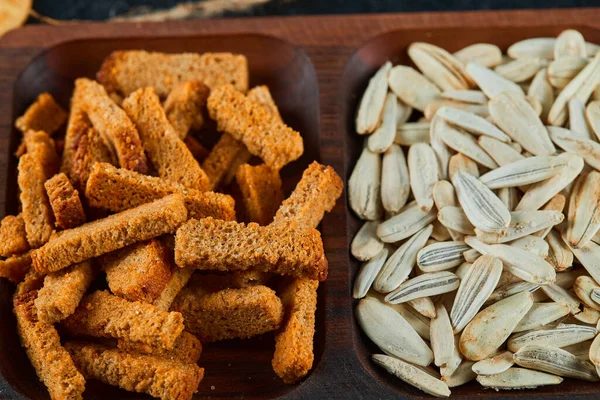 Galletas saladas y snacks de girasol en plato de madera — Foto de Stock