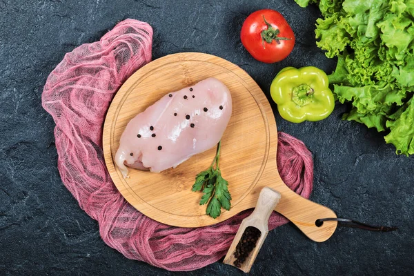 Rauwe kipfilet op houten plank met groenten en tafelkleed — Stockfoto