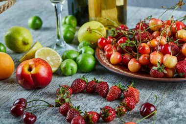 Mermer masada beyaz şaraplı çeşitli yaz meyveleri.