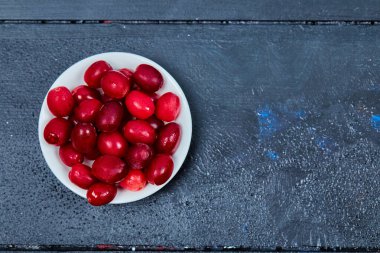 Beyaz tabakta bir sürü kornel çileği. Üst görünüm
