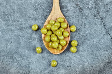 Ahşap bir kaşık kaynamış yeşil bezelye mermer zemin üzerinde