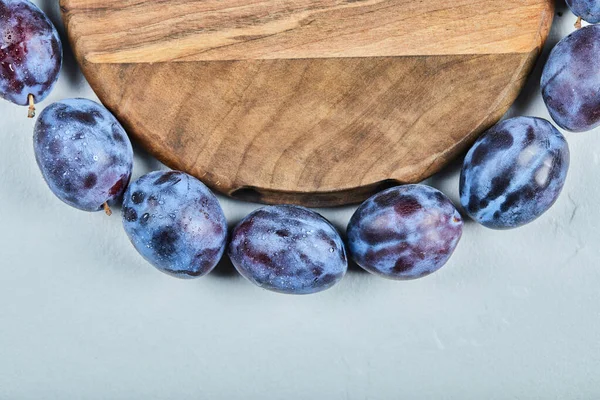Groupe de prunes fraîches autour de la plaque de bois — Photo