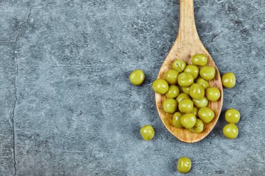 Ahşap bir kaşık kaynamış yeşil bezelye mermer zemin üzerinde