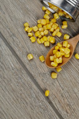 Tahta bir masada kaşıkla haşlanmış mısır konservesi.