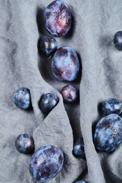Prunes dispersées sur nappe grise — Photo
