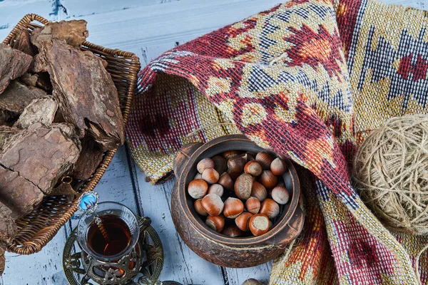 stock image Black tea in a traditional glass cup with candies and a bowl of hazelnuts on blue wooden table