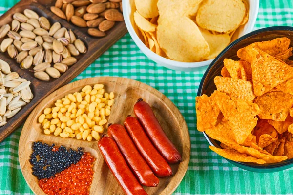 Různé občerstvení, mísa s hranolkami a talíř klobás na modrém stole — Stock fotografie