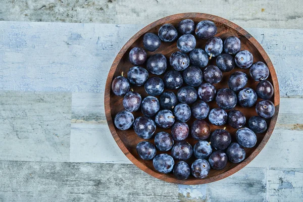 Prunes de jardin dans une assiette sur un fond bleu — Photo