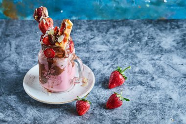 Waffle 'lı çilekli smoothie ve mermer arka plandaki beyaz tabakta çikolata.