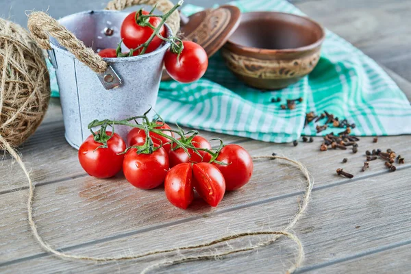 Eimer mit Tomaten und halb geschnittenen Tomaten auf Holztisch mit leerer Schüssel — Stockfoto