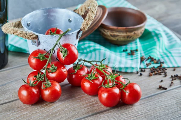Tomatenbündel mit Zweig und leere Schüssel mit Nelken auf Holztisch — Stockfoto
