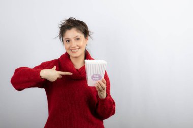 Kazaklı genç kız bir kova patlamış mısırı işaret ediyor.