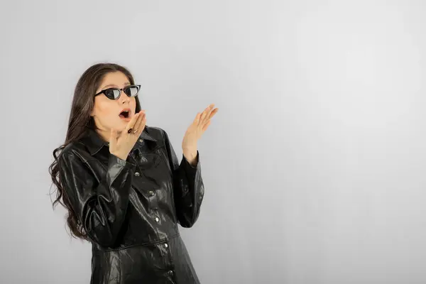 Imagem de uma jovem mulher de casaco preto vestindo óculos e posando — Fotografia de Stock