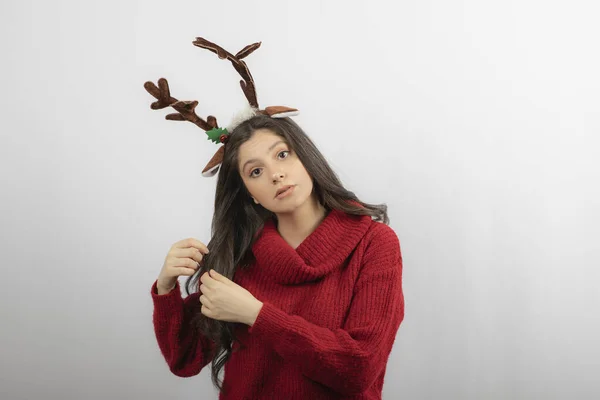 Mladá žena stojí s čelenkou v podobě vánočních rohů — Stock fotografie