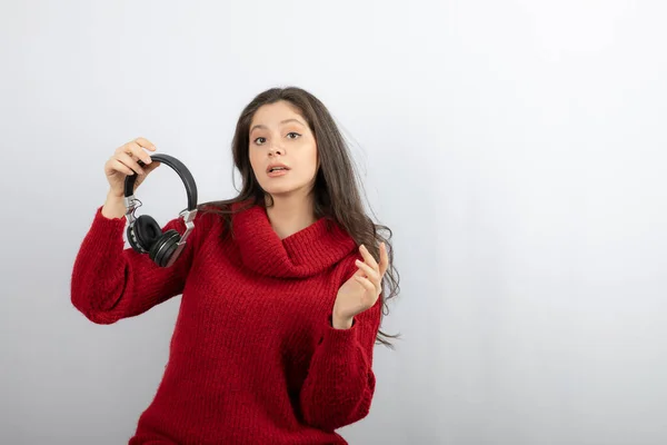 Foto de uma jovem mulher de camisola vermelha tirando fones de ouvido — Fotografia de Stock