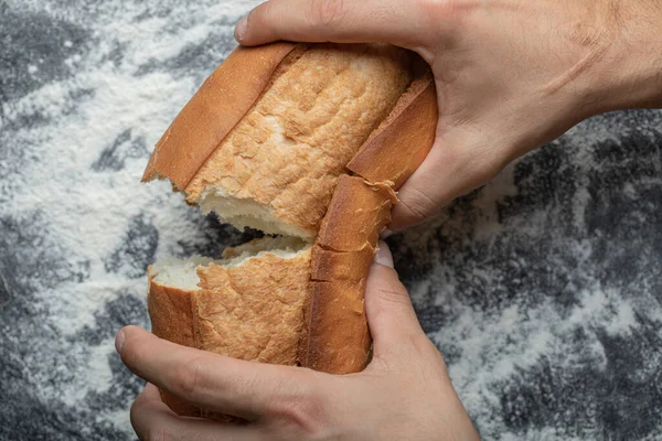 FeMale kéz törés frissen sült kenyér, closeup top view — Stock Fotó