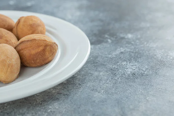 Un plato blanco lleno de galletas dulces en forma de nuez —  Fotos de Stock