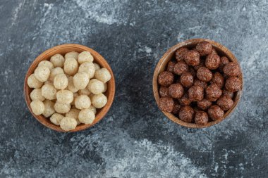 Gri arka planda mısır topları olan ahşap kaseler.