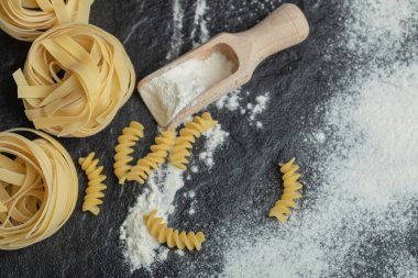 Koyu arkaplanda una bulanmış çiğ erişte.