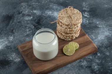 Puffed rice cakes, lemon slice and fresh milk on wooden board