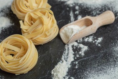 Koyu arkaplanda una bulanmış çiğ erişte.