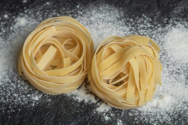 Koyu arkaplanda una bulanmış çiğ erişte.