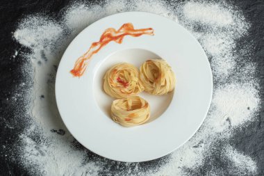 Beyaz bir tabak unlu pişmemiş erişte.