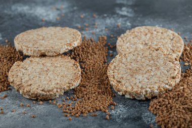 Lezzetli gevrek ekmek ve mermer yüzeyde çiğ karabuğday.