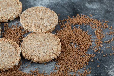 Kabarmış çıtır ekmek ve mermer yüzeyde çiğ karabuğday.