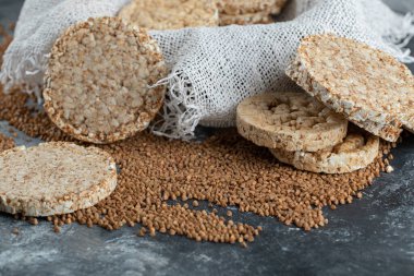 Havadar gevrek ekmek ve mermer yüzeyde çiğ karabuğday.