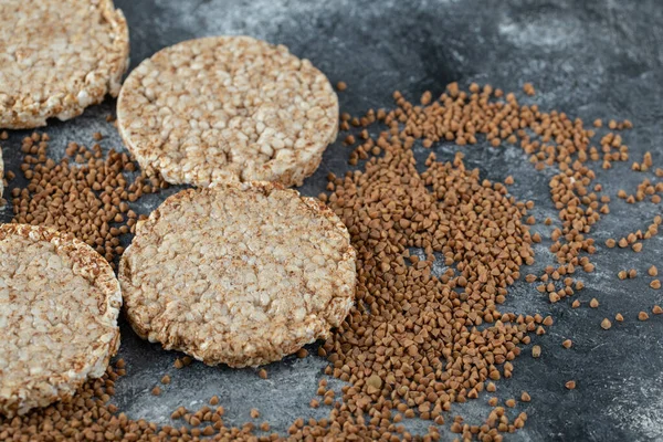 Kabarmış çıtır ekmek ve mermer yüzeyde çiğ karabuğday.