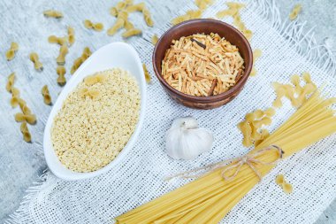 Sarımsaklı mermer zemin üzerinde pişirilmemiş makarna çeşitleri 