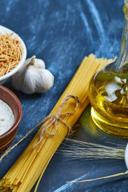 Bir şişe yağ, un ve sarımsaklı çeşitli pişmemiş makarna.