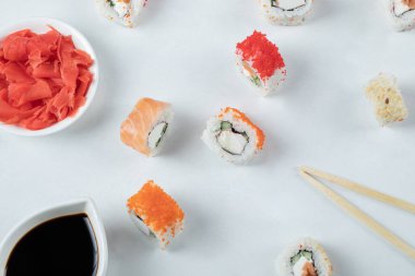 Somonlu suşi ruloları ve beyaz arka planda soya sosuyla servis edilen havyar.