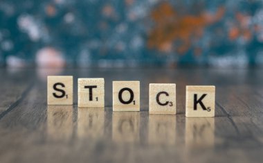 Ahşap zemin üzerindeki tahtadan zarlarda siyah harflerle hisse senedi yazımı