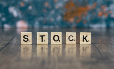 Ahşap zemin üzerindeki tahtadan zarlarda siyah harflerle hisse senedi yazımı