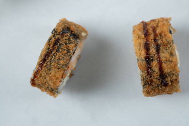 Kızarmış unagi beyaz seramik tabakta yuvarlanıyor.