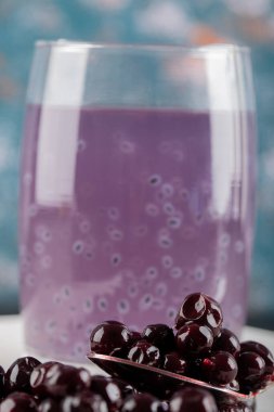 Beyaz bir çay tabağında kuşüzümü ziyareti ve bir bardak meyve suyu.