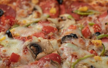 Karışık malzemeli pizza ve üstünde erimiş peynir.