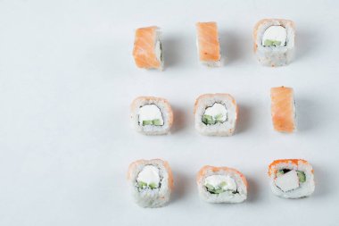 Beyaz arka planda krem peynirli somon ruloları.