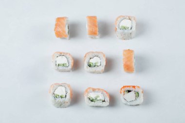 Beyaz arka planda krem peynirli somon ruloları.