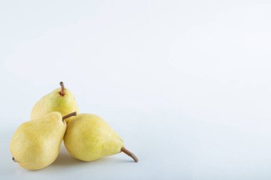 Beyaz arka planda üç sarı armut, yumuşak odak