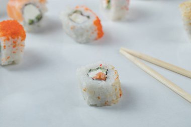 Beyaz arka planda kırmızı havyarlı Maki suşi ruloları.