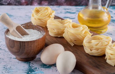 Tahtada un, yumurta ve zeytinyağlı makarna yuvalar.