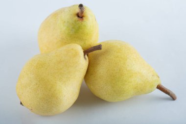 Beyaz arka planda üç olgun armut