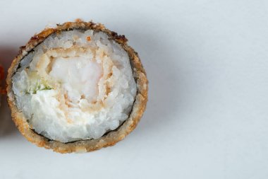 Beyaz arka planda tek bir sıcak suşi rulosu.