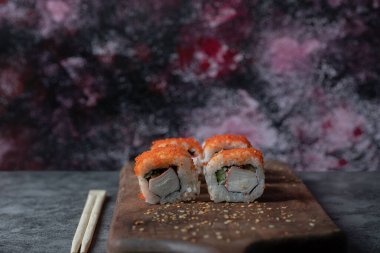 Suşi, deniz ürünleri ve ahşap bir tabakta izole edilmiş kırmızı havyarla yuvarlanır.