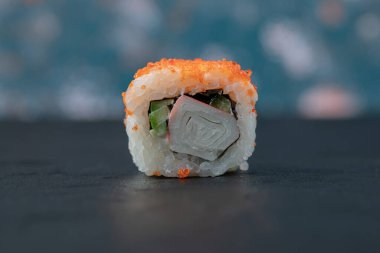 Siyah arka planda izole edilmiş karışık malzemeli suşi rulosu.