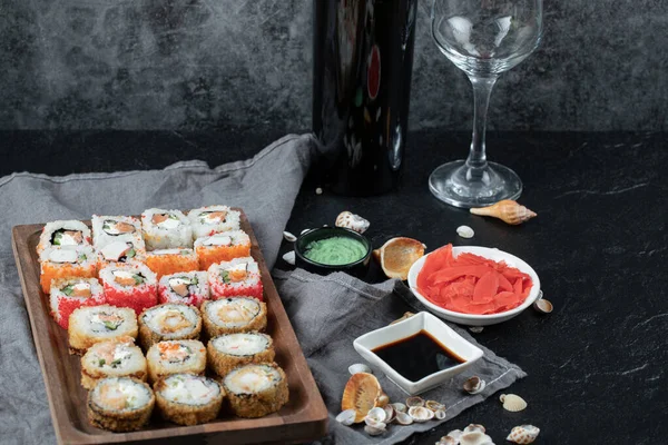 Blandad sushi på en träskiva med flaska och glas vitt vin — Stockfoto